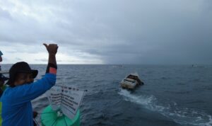 Tokoh masyarakat Pulau Bonetambu mengangkat pelampung dan bendera sebagai penanda resmi dimulainya pembukaan wilayah tangkap gurita, setelah melalui masa penutupan sementara sebagai bagian dari